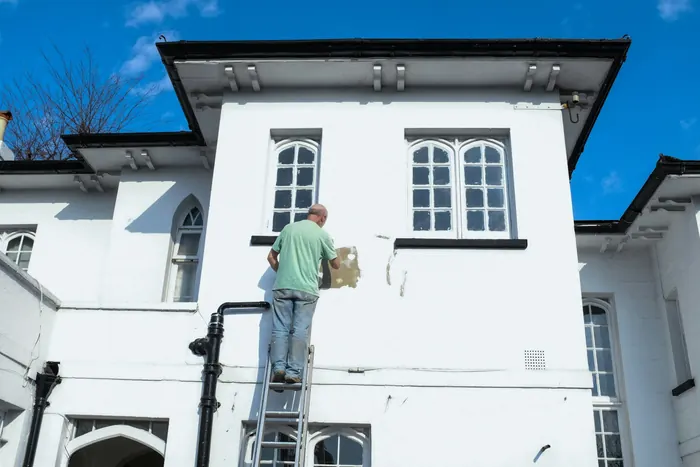 Painter on white concrete building exterior