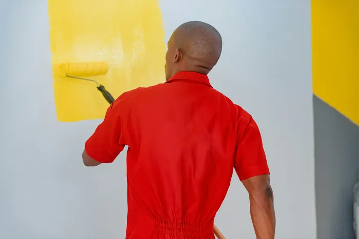 Painter applying golden yellow emulsion to interior wall